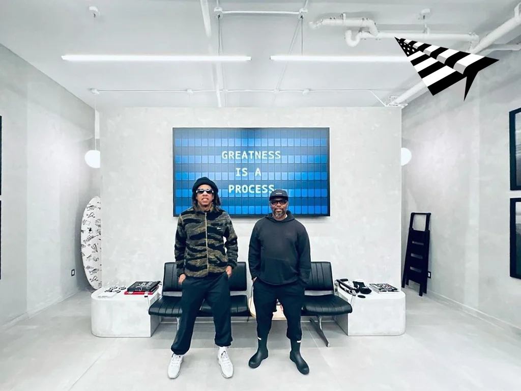 Jay-Z at the Paper Planes store in New York in front of a Split-Flap TV board reading Greatness Is A Process
