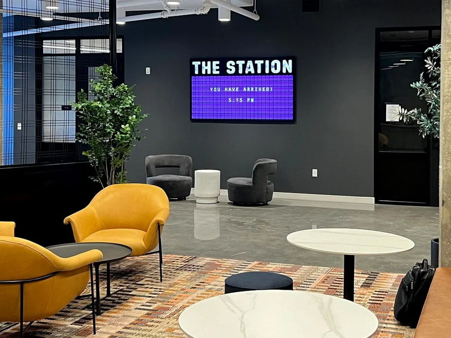 Split-Flap TV welcome board reading The Station, You Have Arrived, in a train-station-themed space