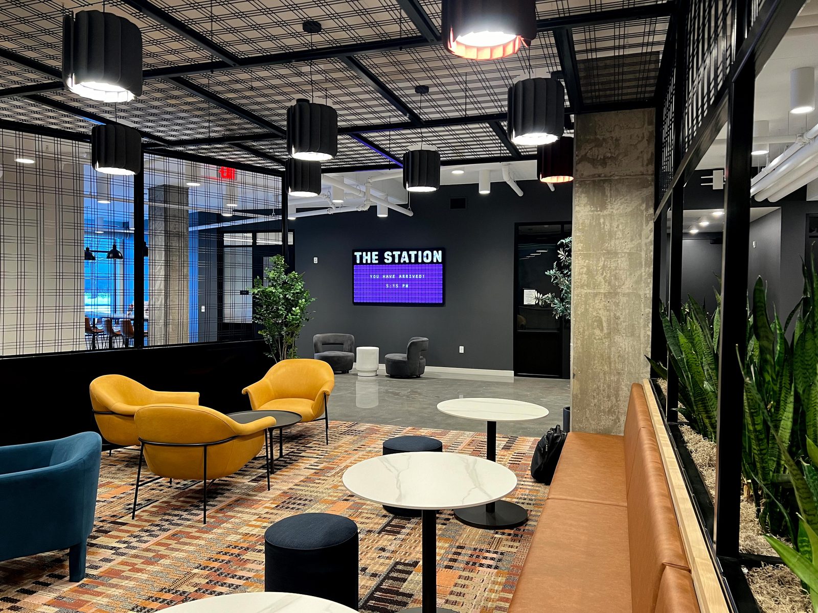 A purple split-flap board reading THE STATION, YOU HAVE ARRIVED in a designer food hall lounge