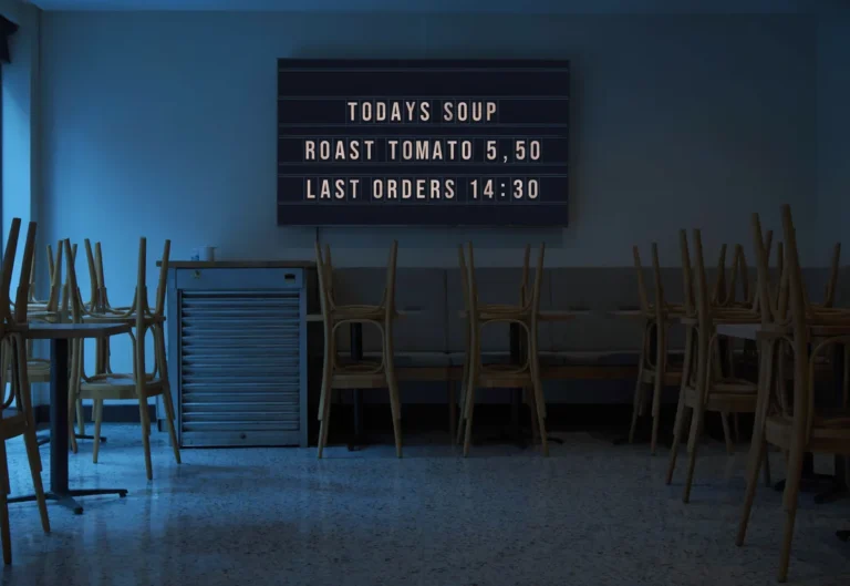An empty cafe before opening with a television showing a split-flap style board of today's soup and last orders.